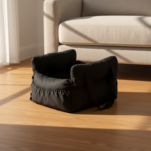 Kodi & Co. black dog car booster seat with cushioned walls and soft fabric, placed on a wooden floor in sunlight.
