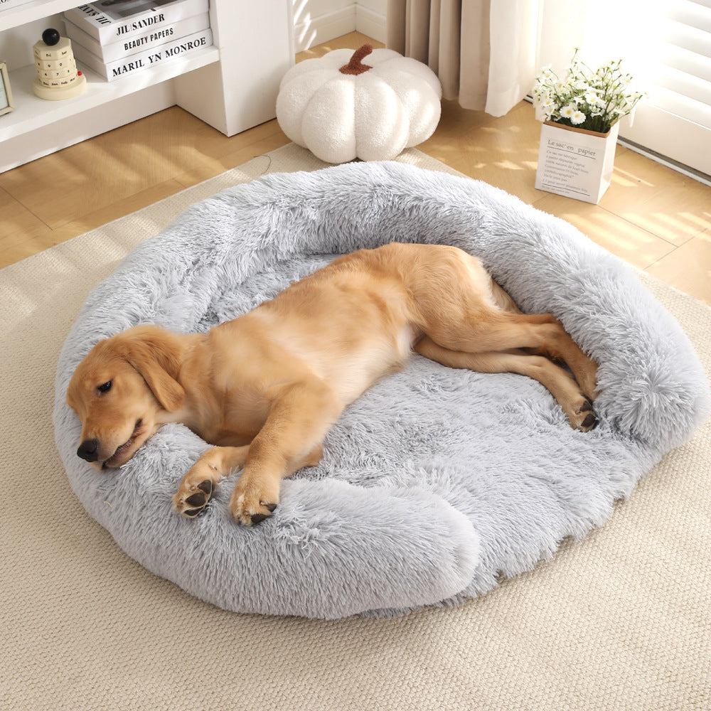 A golden retriever puppy sleeping in a round light gray Kodi & Co. plush dog bed on a beige rug.